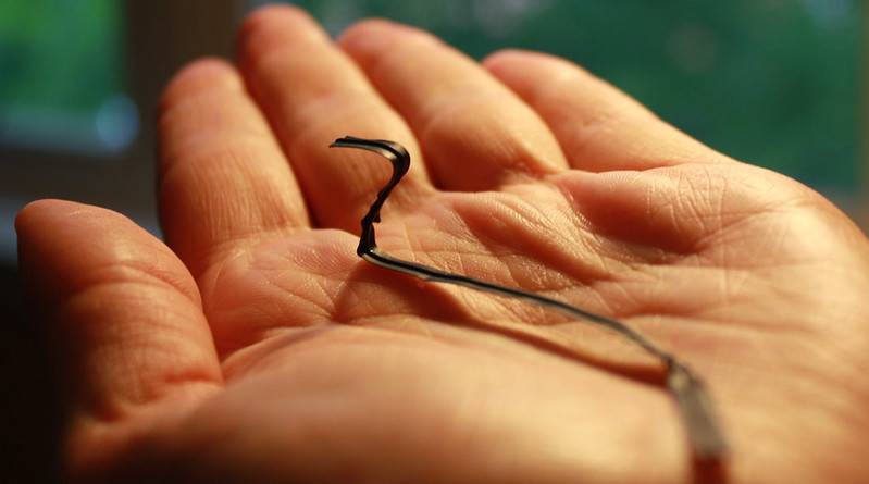 A black twist tie rests in someone's palm.