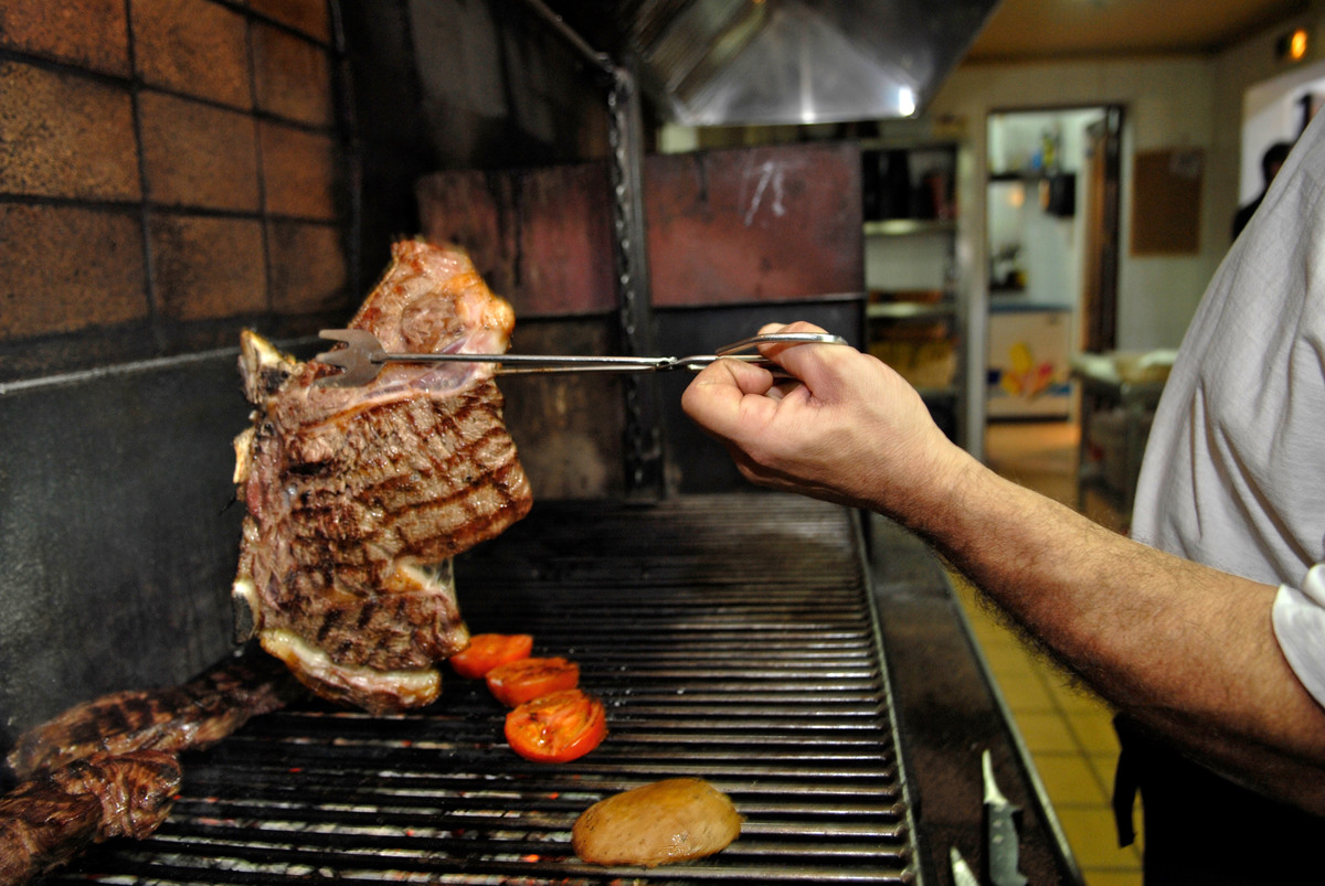 A chef flips steak on a grill.