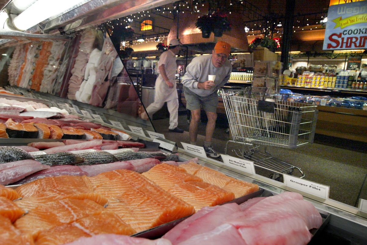 A man shops for farm-raised salmon at a grocery store.