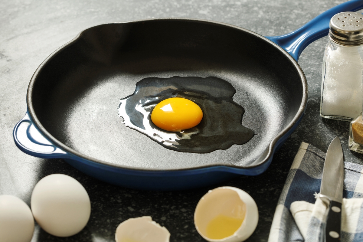 A raw egg is cracked in a frying pan.