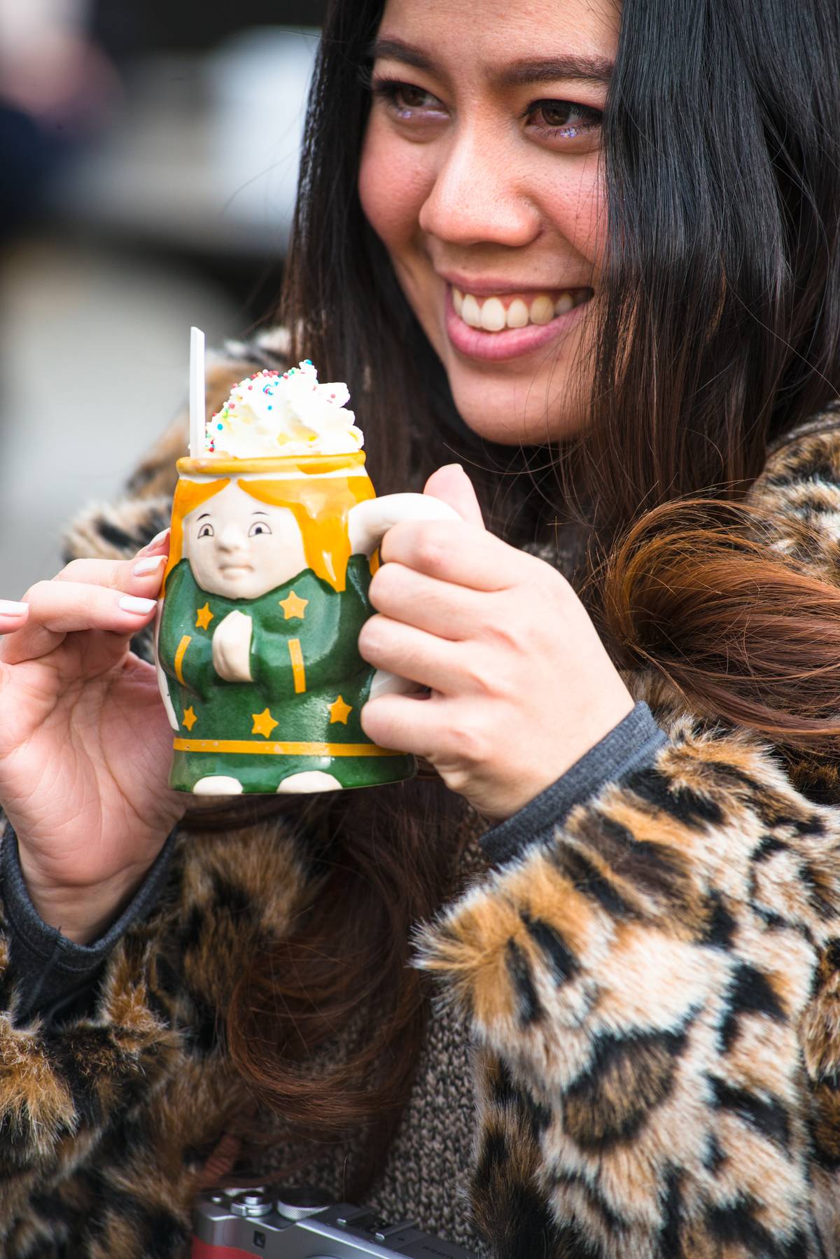A woman enjoys hot chocolate in a Christmas ceramic mug.