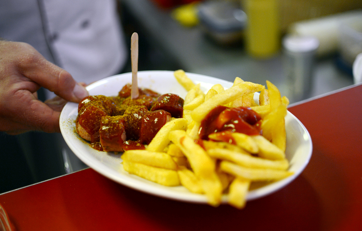 A customer sets down a plate of sausages and fries.