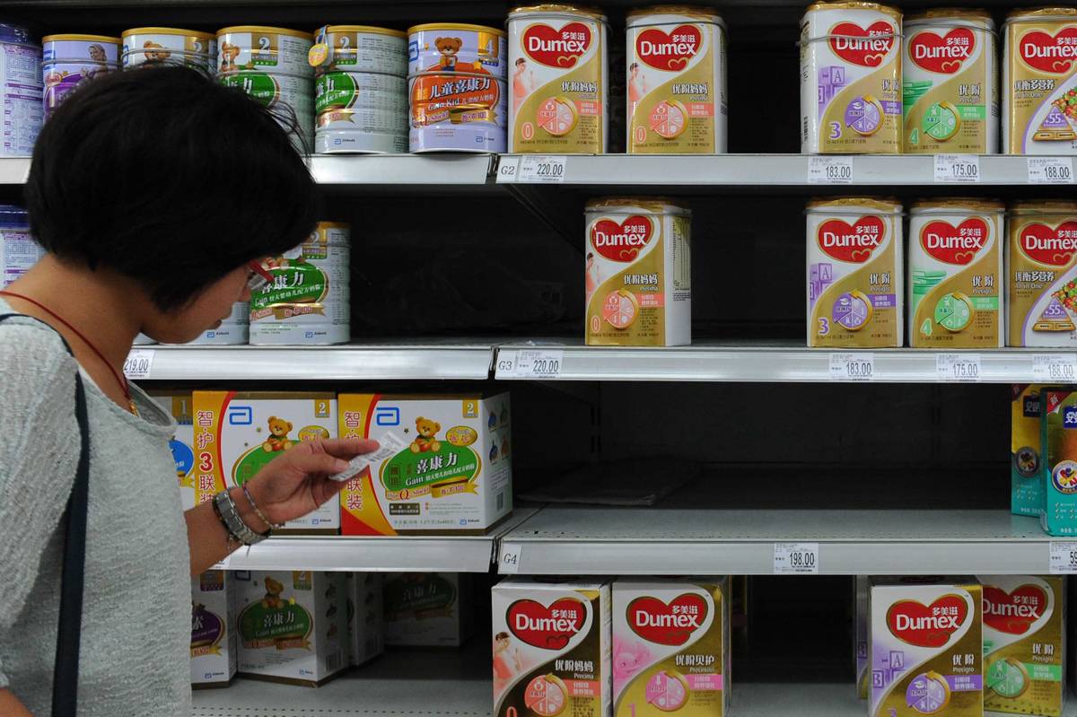 A woman checks the price beside a shelf of Dumex baby formula