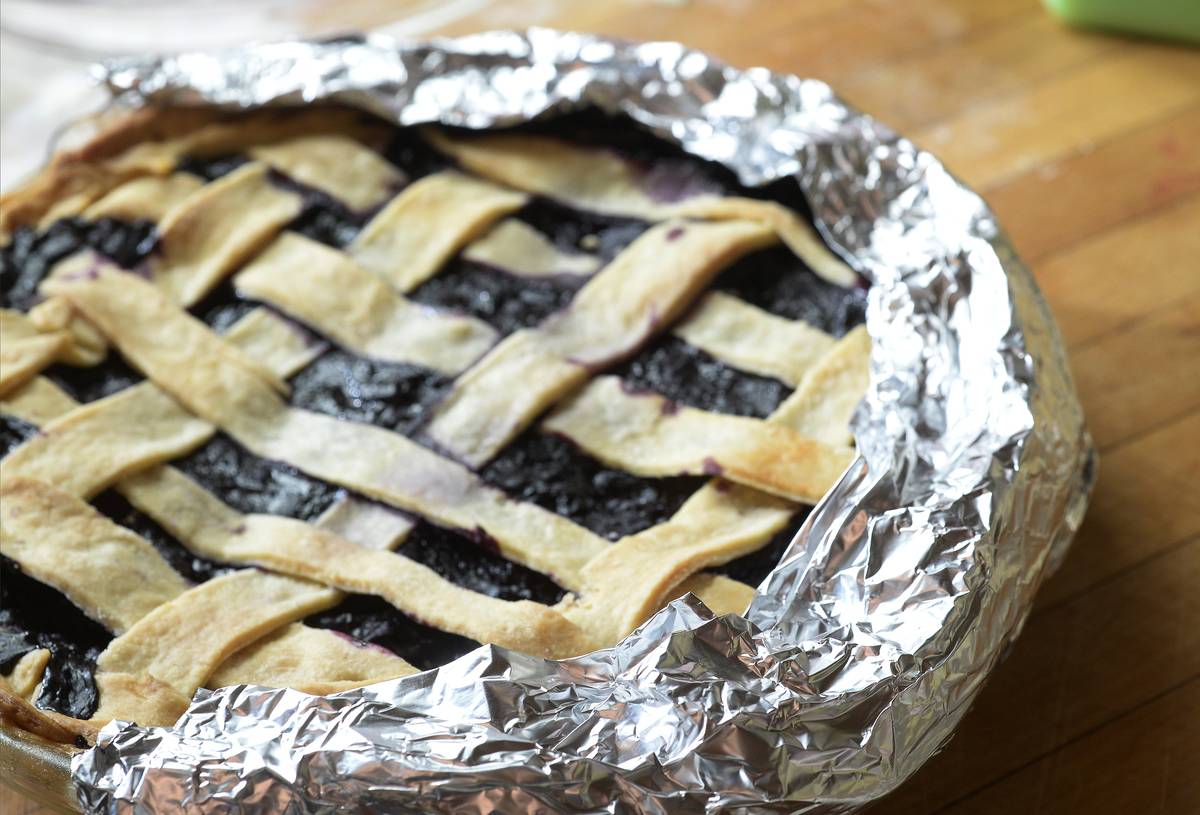 Aluminum foil is wrapped around a pie crust.