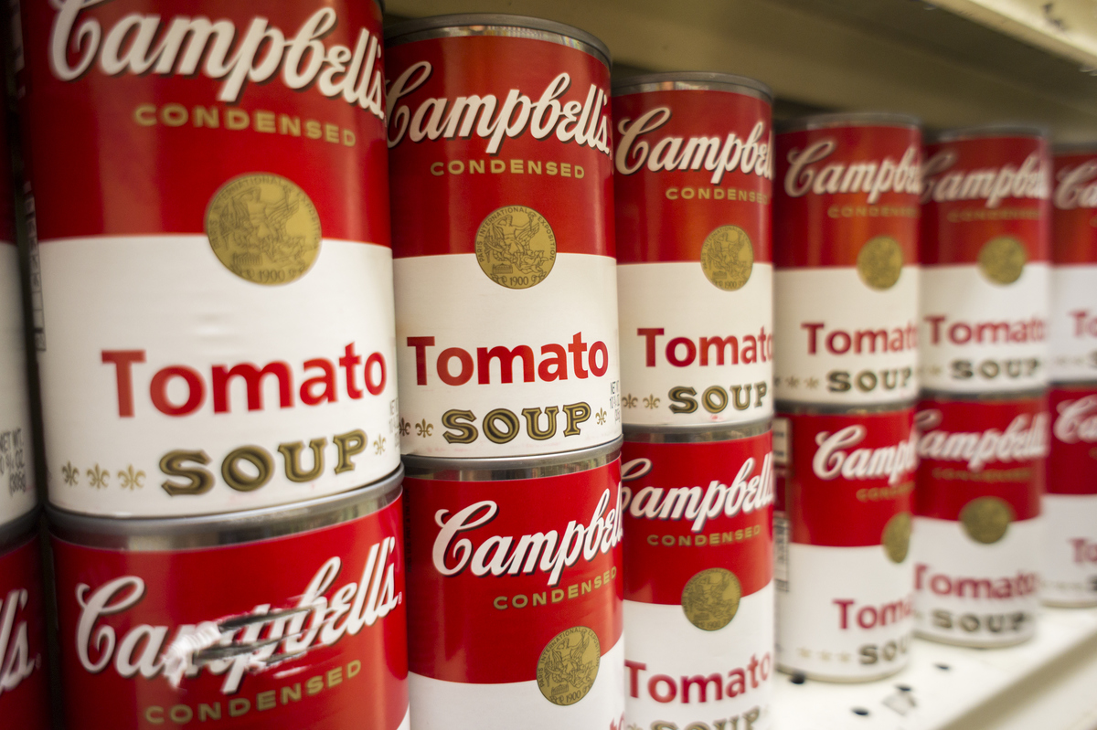 Tomato soup is stacked on a supermarket shelf.