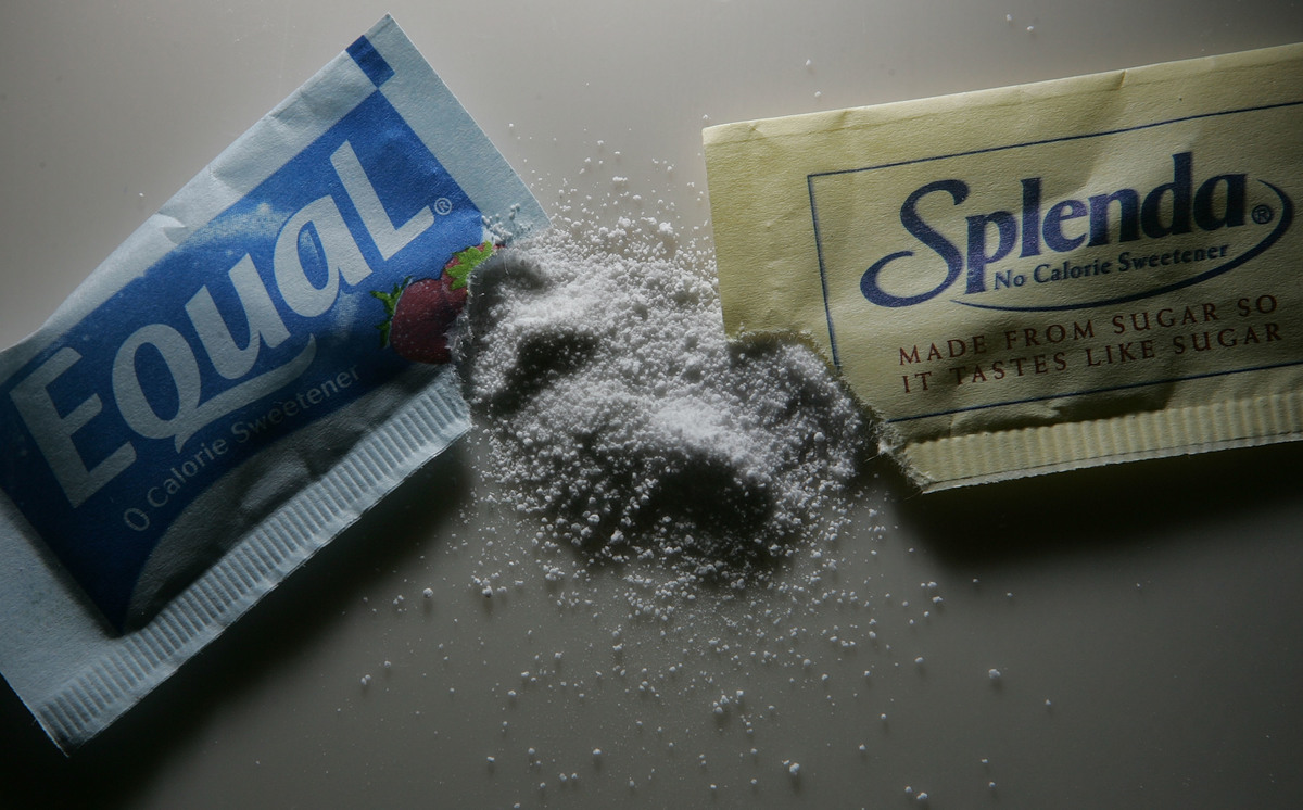 Packages of Equal and Splenda artificial sweeteners are poured onto a coffee table.