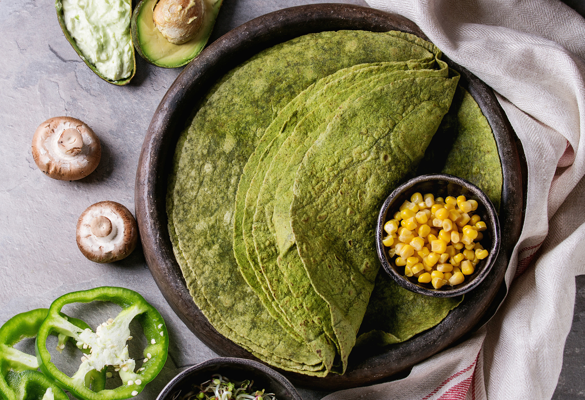 A bowl of corn sits next to spinach and matcha corn tortillas.