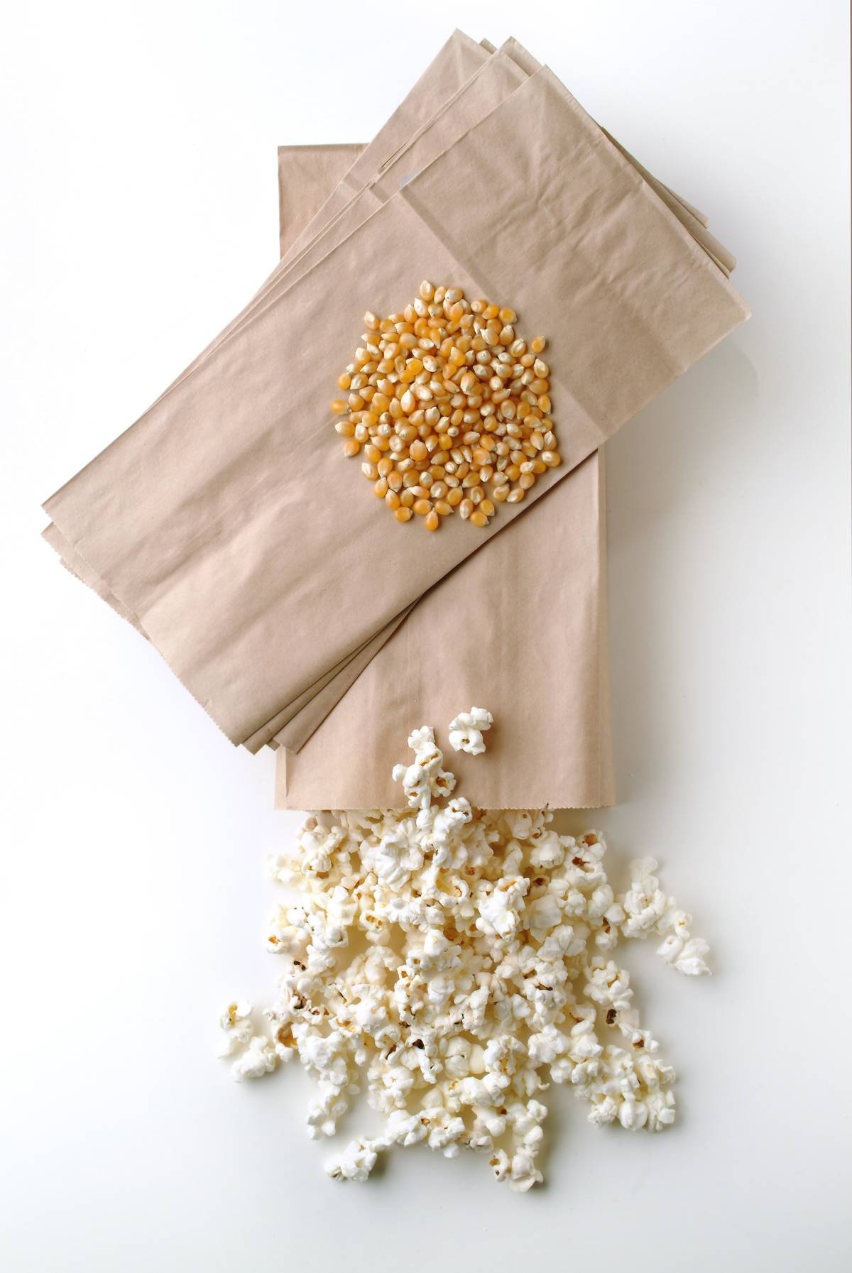 Popcorn pours out of a brown paper bag.