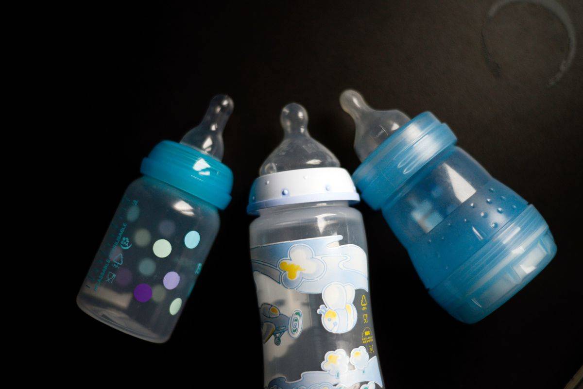 Three baby bottles lie on a table.