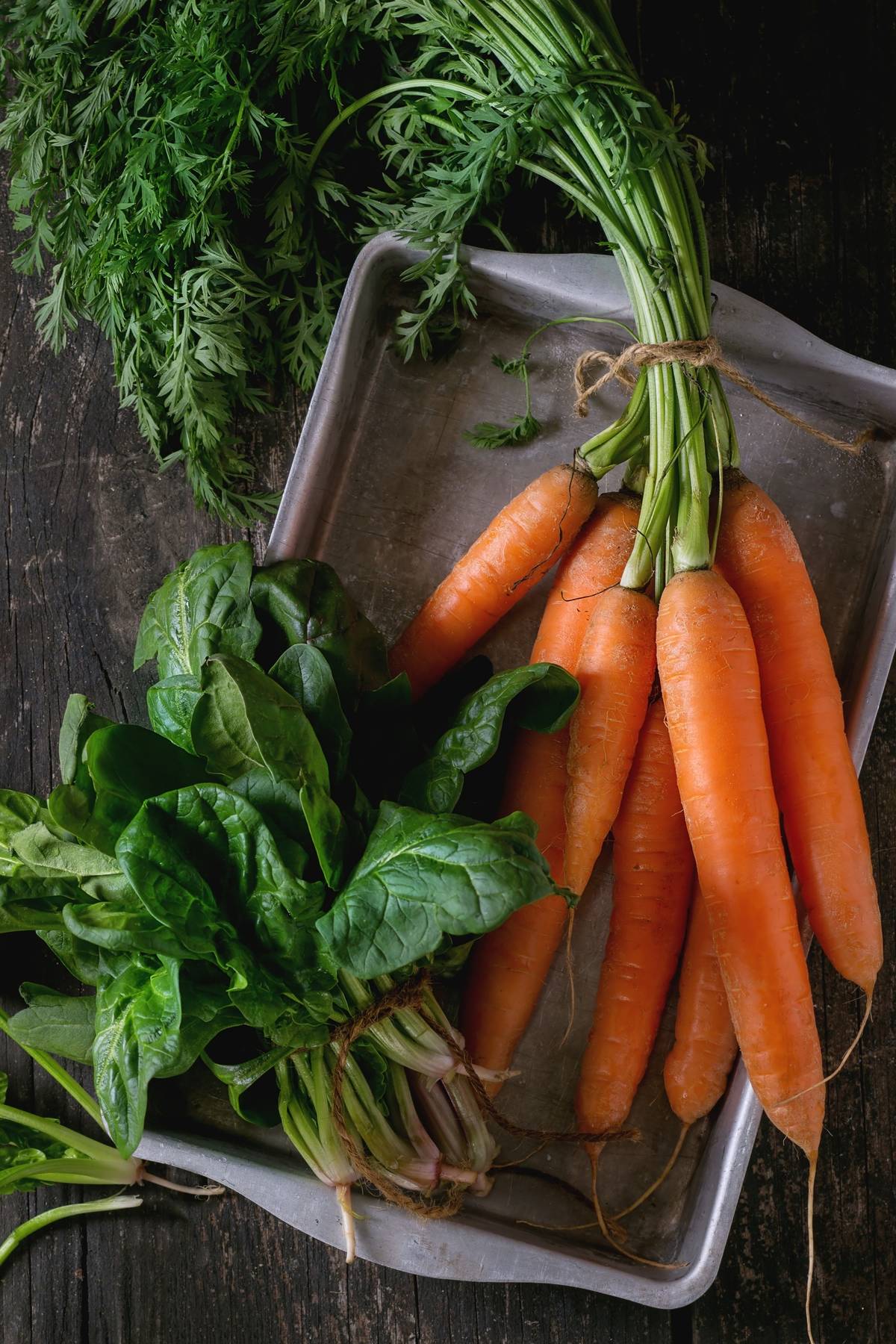 Carrots and spinach, two nitrate-heavy vegetables, lie on a baking tray.