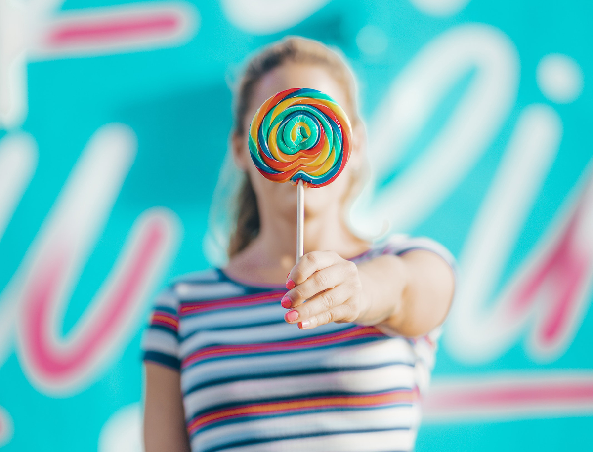 A woman holds up a lollipop.