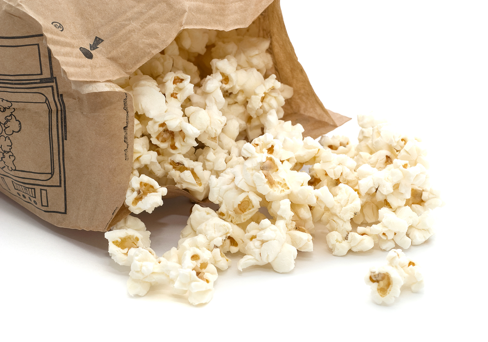 Popcorn pours out of a microwavable bag.