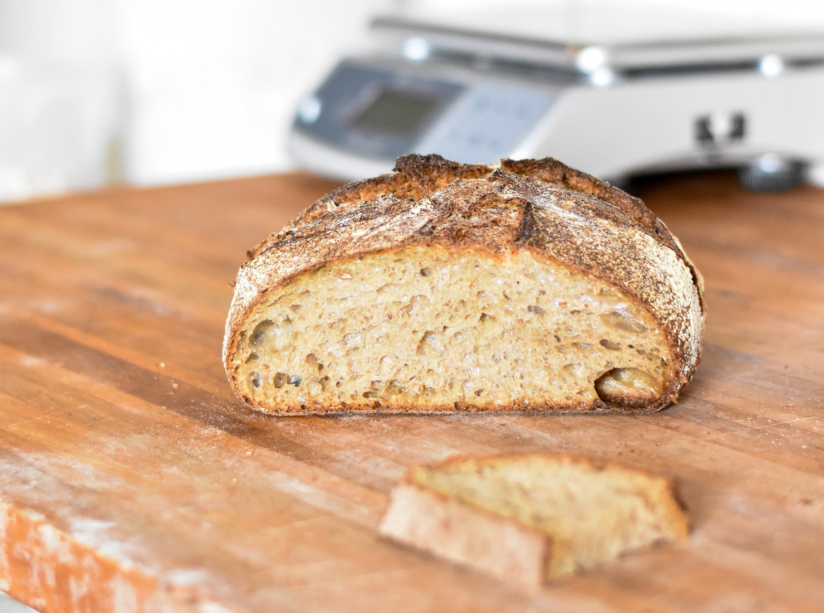 Sliced sourdough bread lies on a wooden cutting board.