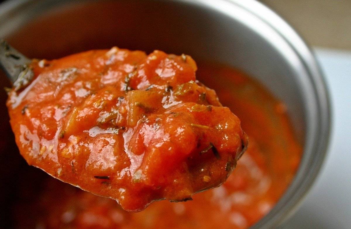 A spoon scoops up some tomato sauce.