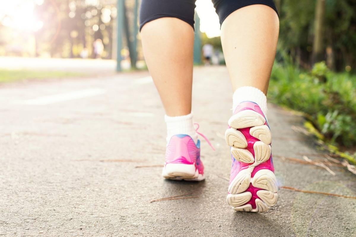 A close-up photo shows a woman's feet while walking outdoors.