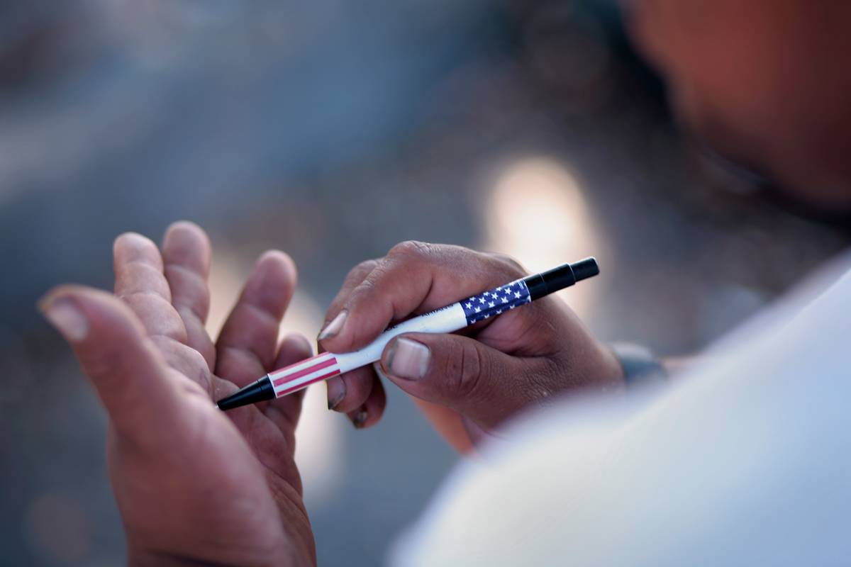 A man writes on his hand with a pen.